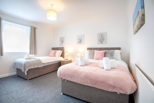 1 dormitorio con 2 camas y ventana en Stop Looking! Walk to the City Center - TV in every Bedroom!, en Swansea