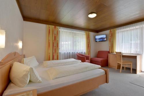 a bedroom with a bed and a chair and a television at Gästehaus Hoamatl in Mayrhofen