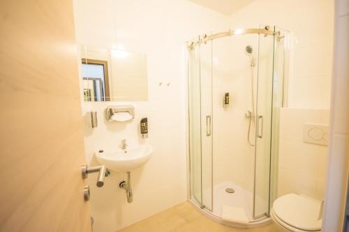 a bathroom with a shower and a toilet and a sink at Hotel Turmfalke in Linz