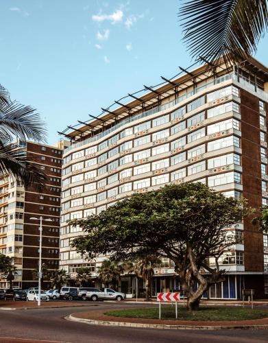 a large building with a tree in front of it at Belaire Suites Hotel in Durban