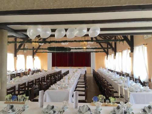 une grande salle de banquet avec des tables et des chaises blanches dans l'établissement Hotel-Gasthof Grüner Hof, à Freising