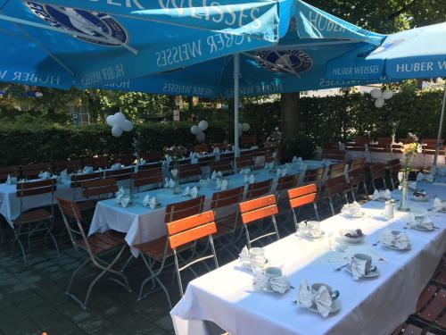 eine Gruppe von Tischen mit Stühlen und blauen Sonnenschirmen in der Unterkunft Hotel-Gasthof Grüner Hof in Freising