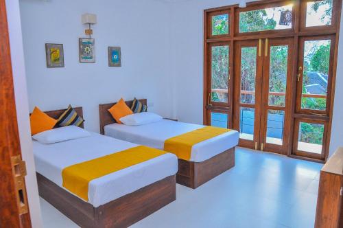 a bedroom with two beds and a window at Amuththa Resort in Anuradhapura