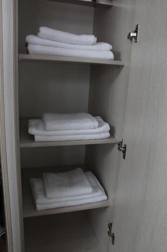 a closet with white towels and folded towels at Апарт отель Welcome in Taldykorgan