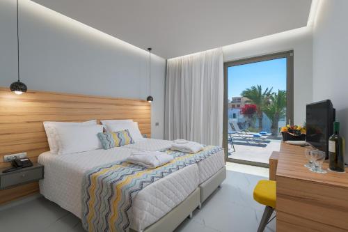 Dormitorio con cama, escritorio y TV en Avra Beach Resort en Ixia