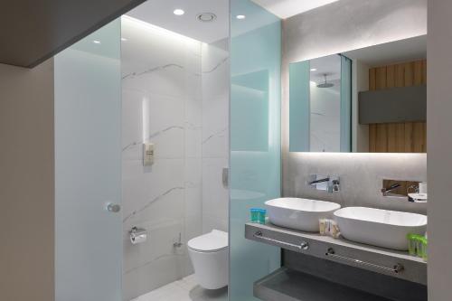 a bathroom with two sinks and a toilet and a mirror at Avra Beach Resort in Ixia