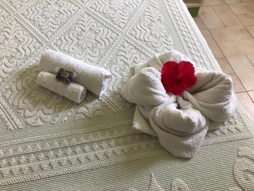 two towels and a red flower on a bed at B&B La Pintadera in Santa Teresa Gallura