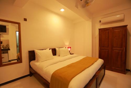 a bedroom with a large bed and a mirror at Opulence Colombo in Colombo