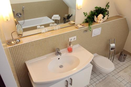 e bagno con lavandino, servizi igienici e vasca. di Hotel Weinblatt a Sommerach