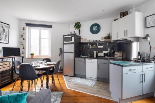 een keuken met witte kasten en een tafel met een eetkamer bij Le Plongeoir by Cocoonr in Saint-Malo