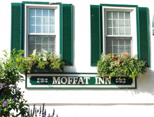 a sign on a building with two windows and flowers at Moffat Inn in Niagara on the Lake