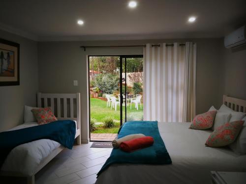 a bedroom with two beds and a sliding glass door at Chic Breeze in Bloemfontein