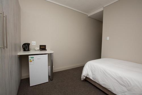 a small room with a bed and a white refrigerator at 14 on Marine in East London