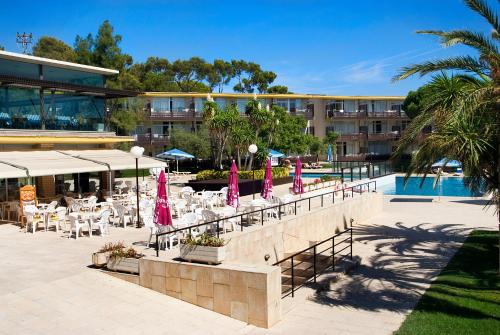 un complejo con piscina, mesas y sombrillas rosas en Aparthotel Comtat Sant Jordi en Platja  d'Aro