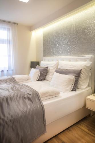 a white bed with white pillows in a bedroom at Főtér Rezidencia in Győr