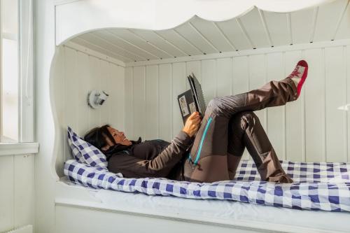 Eine Frau, die auf einem Bett liegt, mit den Füßen auf einem Buch in der Unterkunft Malungs Camping in Malung
