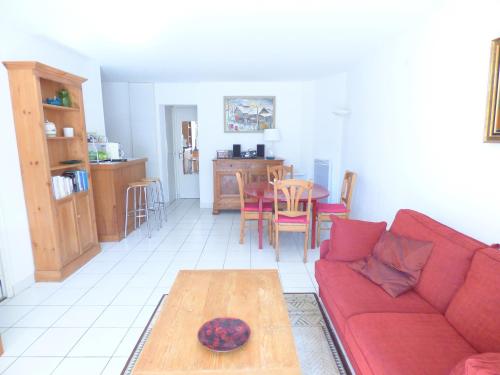 a living room with a red couch and a table at En plein coeur de l'éventail de Cabourg - Résidence "CARLOTTA" Jolie villa divisée en appartement à deux pas de la m in Cabourg