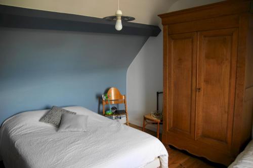 Schlafzimmer mit einem weißen Bett und einem Holzschrank in der Unterkunft JOLIE PROPRIÉTÉ "VILLA CAMELIA" EN PLEIN COEUR DE L'EVENTAIL DE CABOURG in Cabourg