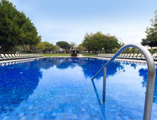 
a person standing in a pool with a blue umbrella at Dom Pedro Vilamoura in Vilamoura
