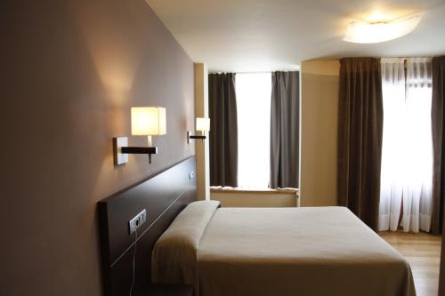 a hotel room with a bed and two windows at Hotel Baltico in Luarca