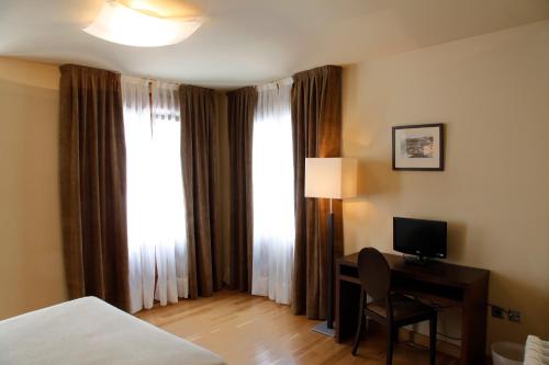 a hotel room with a desk with a computer and a window at Hotel Baltico in Luarca