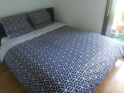 uma cama com um edredão preto e branco num quarto em Sombang em Ferney-Voltaire