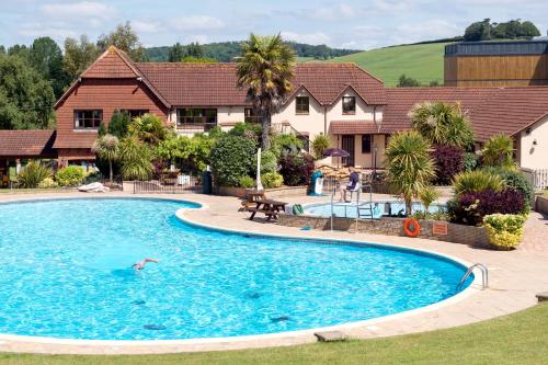 una persona che nuota in una piscina in una casa di Cofton Holidays a Dawlish