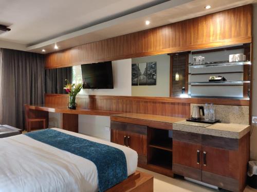 a bedroom with a bed and a desk with a tv at Fairway Boutique Hotel - Kampala, Uganda in Kampala
