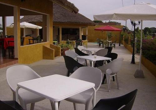 a patio with white tables and chairs and umbrellas at Le Petit Quartier "Chez Amanthia" in Cap Skirring
