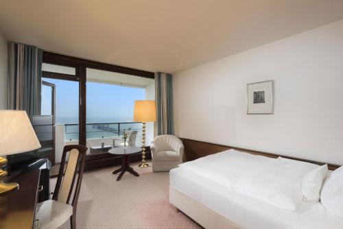 a hotel room with a bed and a desk and a window at Maritim Seehotel Timmendorfer Strand in Timmendorfer Strand