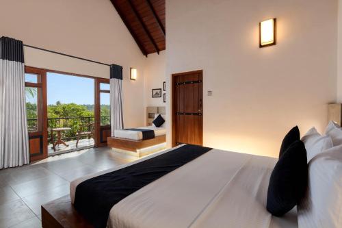 a bedroom with a large bed and a balcony at Kubura Resort in Anuradhapura