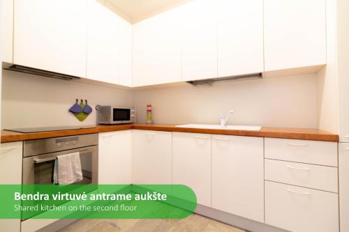 Una cocina vacía con gabinetes blancos y un fregadero. en Vila Primavera, en Palanga