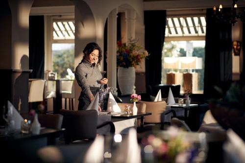 a woman standing in a room with tables and chairs at Van der Valk Hotel De Molenhoek-Nijmegen in Molenhoek