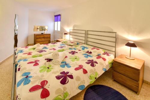 1 dormitorio con 1 cama con colcha de flores en Apartamento Ferrera Park 602, en Cala Ferrera