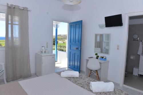 Habitación blanca con puerta azul y baño. en Agkira Studios Milos, en Provatas