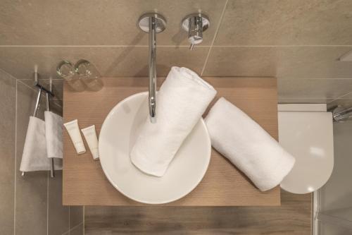 un lavandino in bagno con asciugamani bianchi su un bancone di Schlosshof Charme Resort – Hotel & Camping a Lana