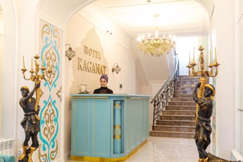 a woman standing behind a counter in a hallway with stairs at Hotel Kaganat in Kazan