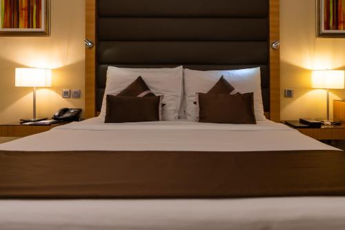 a bedroom with a large bed with two pillows at Copthorne Hotel Sharjah in Sharjah