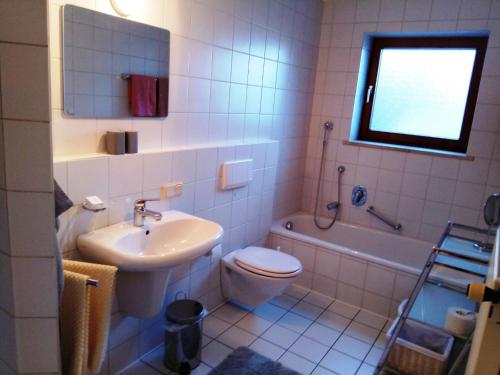 a bathroom with a sink and a toilet and a tub at Ferienwohnung Elgert in Scheidegg
