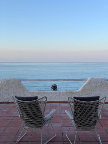 two chairs sitting on a patio overlooking the ocean at Villa Anna in Agnone Bagni