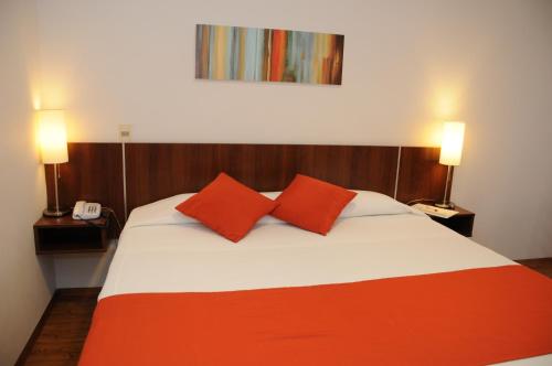 a bedroom with a bed with two red pillows at Hotel California in Montevideo