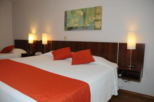 a bedroom with a large bed with two red pillows at Hotel California in Montevideo