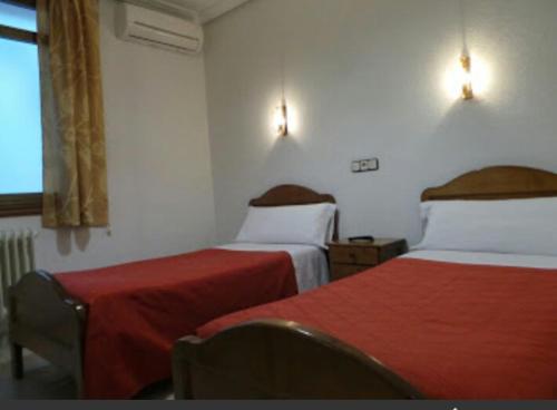 Cette chambre d'hôtel comprend 2 lits avec des draps rouges. dans l'établissement Hostal Gaudí, à Madrid
