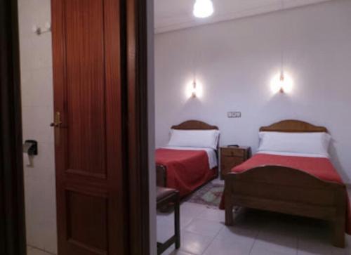 1 dormitorio con 2 camas con sábanas rojas y blancas en Hostal Gaudí, en Madrid
