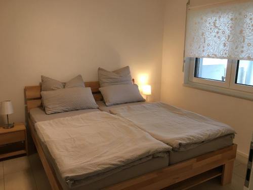 een bed met witte lakens en kussens in een slaapkamer bij Ferienwohnung Gluiber in Beuren