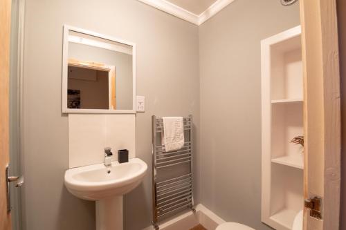 ein weißes Badezimmer mit einem Waschbecken und einem Spiegel in der Unterkunft Guest Homes - Hanover Apartment in Swansea