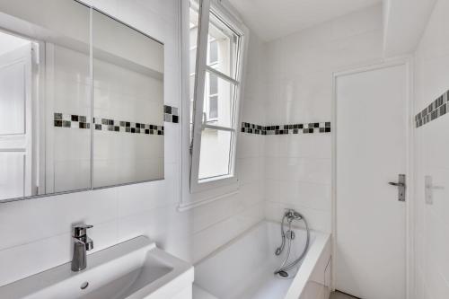 une salle de bain blanche avec un lavabo et un miroir dans l'établissement Design apartment with terrace by Weekome, à Paris