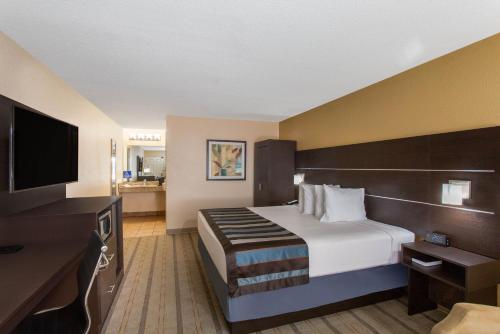 a hotel room with a bed and a flat screen tv at Baymont by Wyndham Punta Gorda/Port Charlotte in Punta Gorda