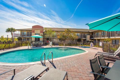 a swimming pool with tables and chairs and a building at Baymont by Wyndham Punta Gorda/Port Charlotte in Punta Gorda