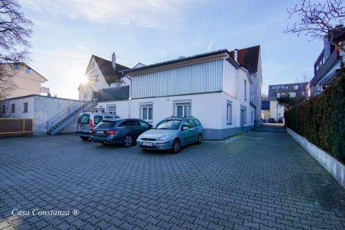 zwei Autos auf einem Parkplatz neben einem Gebäude geparkt in der Unterkunft Casa Constanza Hotel Garni in Friedrichshafen